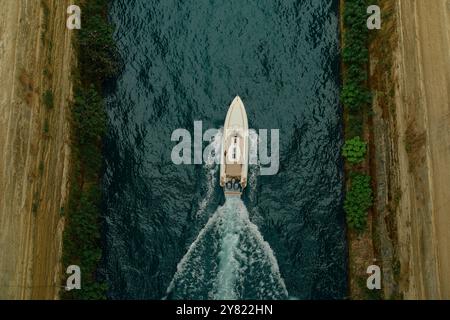 Vista aerea di un motoscafo bianco che naviga attraverso uno stretto canale d'acqua fiancheggiato da foglie verdi. Foto Stock