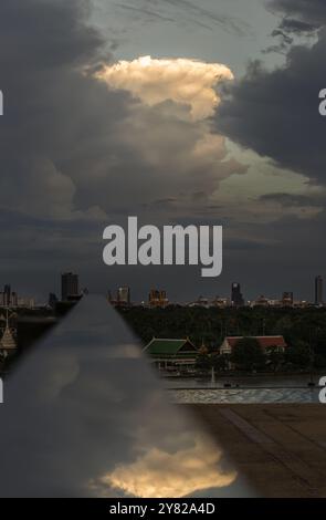 Il cielo è coperto da nuvole incredibili con riflessi su corrimano in acciaio inox con vista sulla città lungo il fiume. Concetto di fantasia c Foto Stock