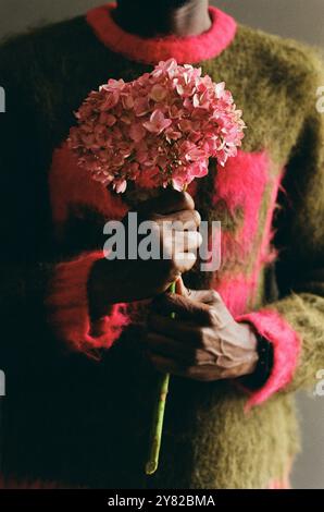 Primo piano verticale di un giovane irriconoscibile con fiori rosa in fiore girato su film in studio Foto Stock