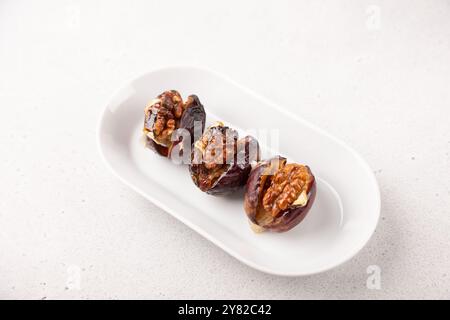 Prugne cotte al forno con formaggio Camembert, noci e miele su un piatto bianco. Popolare antipasto caldo. Messa a fuoco selettiva, primo piano. Foto Stock