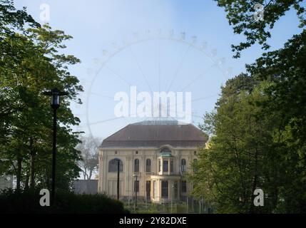 Kuehlungsborn, Germania - 30 maggio 2021: Nebbia luminosa sulla ruota panoramica dietro la Villa Baltica circondata da alberi verdi in una serata primaverile nel nord del G Foto Stock