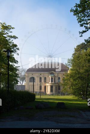 Kuehlungsborn, Germania - 30 maggio 2021: Nebbia luminosa sulla ruota panoramica dietro la Villa Baltic in una serata primaverile nel nord della Germania. Foto Stock