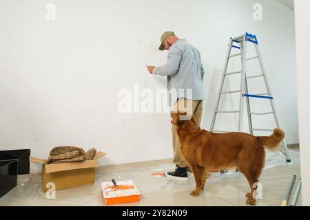 Colpo medio dal retro di un uomo in abiti casual che ristrutturano la sua nuova casa Foto Stock