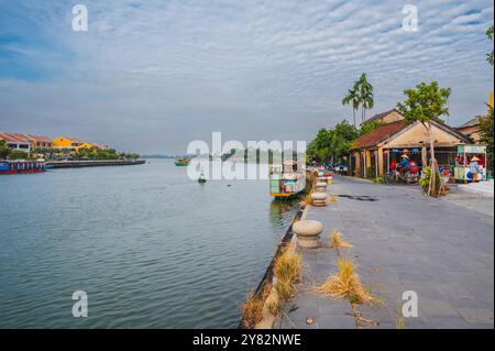 Terrapieno sul fiume Thu bon con barche nella città vecchia di Hoi An in Vietnam in estate. Hoi An, Vietnam - 12 settembre 2024 Foto Stock