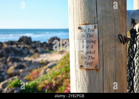 Un cartello su un palo vicino all'oceano che dice ci vediamo al mattino per fare snorkeling sulla barriera corallina, Mettams Pool, Perth, Australia Occidentale. Foto Stock