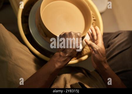 Primo piano di un produttore di ceramiche africane che forma una ciotola che gira su una ruota usando le dita in uno studio di ceramica Foto Stock