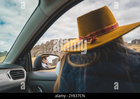 Una donna che indossa un cappello giallo è seduta in macchina e guarda fuori dal finestrino. Foresta di pietra di Huayllay, Perù. Foto Stock