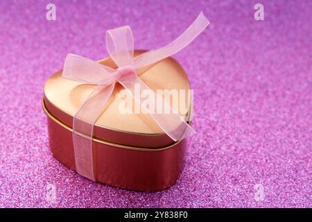 Confezione regalo a forma di cuore dorato con fiocco rosa Foto Stock