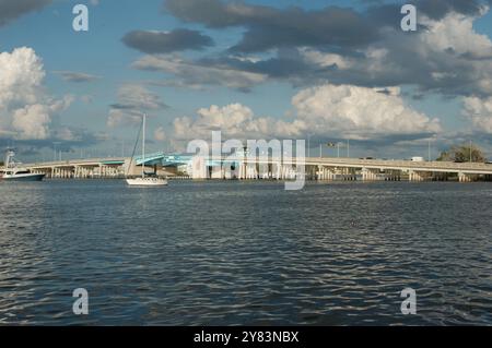 Vista dall'altra parte della costa verso Corey Causeway Drawbridge aperto di colore blu. Due barche a vela al centro e altre barche che si dirigono sotto il ponte. Puffy Foto Stock