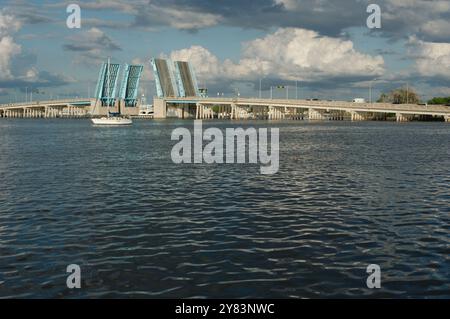 Vista dall'altra parte della costa verso Corey Causeway Drawbridge aperto di colore blu. Due barche a vela al centro e altre barche che si dirigono sotto il ponte. Puffy Foto Stock