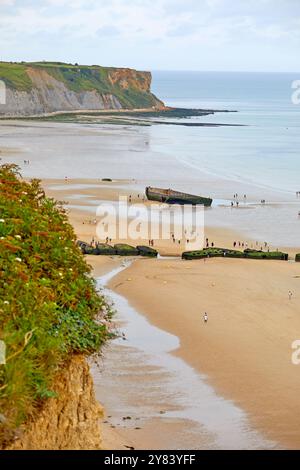 Visitatori che esplorano i resti di Mulberry Harbour, Arromanches Beach, Normandia Francia Foto Stock