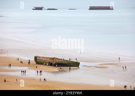 Visitatori che esplorano i resti di Mulberry Harbour, Arromanches Beach, Normandia Francia Foto Stock