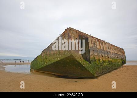 Visitatori che esplorano i resti di Mulberry Harbour, Arromanches Beach, Normandia Francia Foto Stock