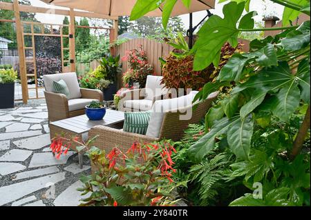 Patio dell'oasi giardino con lussureggianti piante tropicali e vegetazione, posti a sedere in stile caffetteria, ambiente mediterraneo estivo Foto Stock