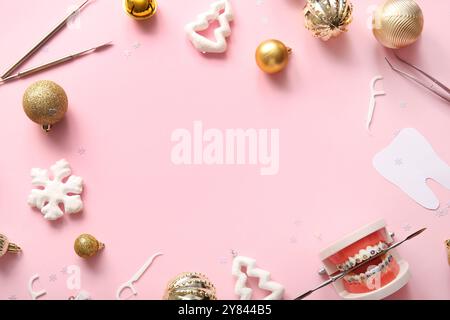 Cornice realizzata con strumenti da dentista e decorazioni natalizie su sfondo rosa Foto Stock