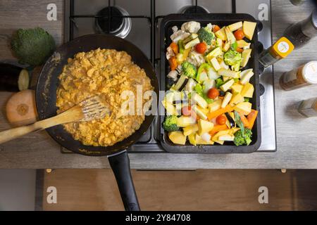 Piano cottura con vista dall'alto, teglia wok di curry indiano fatto in casa e vassoio da forno di verdure fresche e colorate pronte per cucinare Foto Stock