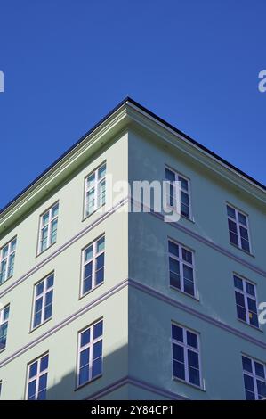 Un angolo verde di un edificio con molte finestre che si affacciano su un cielo azzurro, Bergen, Vestland, Norvegia, Europa Foto Stock