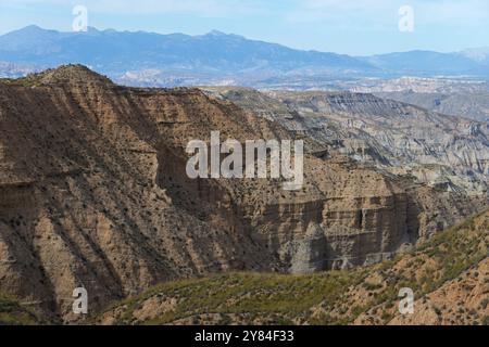 Paesaggio desertico collinare e asciutto con montagne sullo sfondo sotto un cielo azzurro, deserto di Gorafe, Granada, Andalusia, Spagna, Europa Foto Stock