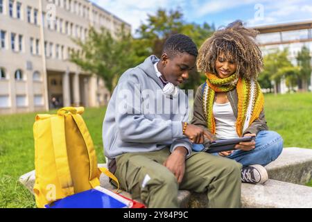 Due studenti universitari di sesso maschile e femminile che utilizzano un tablet digitale fuori dal campus Foto Stock