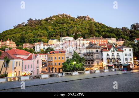 SINTRA, Portogallo - il castello moresco (Castelo dos Mouros) si erge in cima a una collina sopra la città di Sintra. Questa fortezza medievale, con i suoi muri di pietra che serpeggiano lungo il ridgeline, offre una spettacolare silhouette contro il cielo e offre una vista dominante del paesaggio circostante. Foto Stock