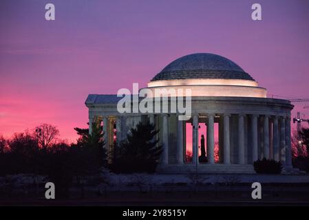 Jefferson Memorial silhouette Sunrise Washington DC // WASHINGTON DC - il Jefferson Memorial si staglia contro i cieli rosa prima dell'alba in questa vista dal lato occidentale del monumento. La statua di Thomas Jefferson si erge in modo prominente al centro della cornice, creando una silhouette drammatica all'interno della struttura a cupola del memoriale neoclassico. Completato nel 1943, il memoriale onora il terzo presidente americano e autore principale della dichiarazione di indipendenza. Il memoriale, progettato dall'architetto John Russell Pope, si trova lungo il bacino delle maree nel West Potomac Park. Le sfumature rosa di Foto Stock