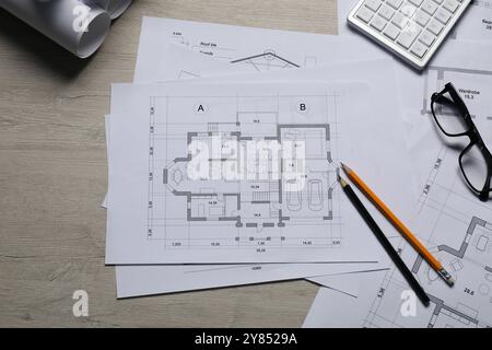 Diversi disegni architettonici, calcolatrice, vetri e matite su tavolo in legno, vista dall'alto Foto Stock