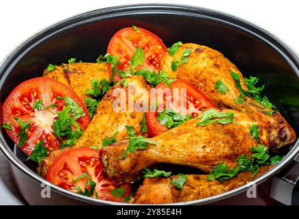 Cosce di pollo al forno dorate con pomodori e prezzemolo. Foto Stock