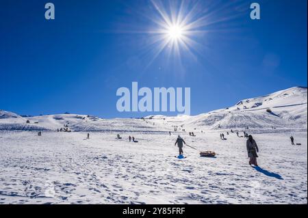 In inverno, in una giornata di sole, le persone corrono in discesa sul tubing. Shymkent, Kazakistan - 27 gennaio 2024 Foto Stock