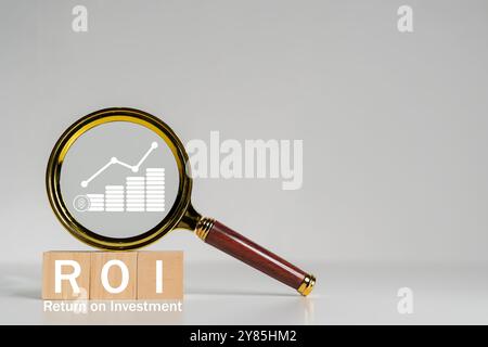 Analisi del concetto di ritorno sugli investimenti (ROI). Uomo d'affari in possesso di una lente d'ingrandimento con ROI e varie icone finanziarie, che rappresentano l'analisi o Foto Stock