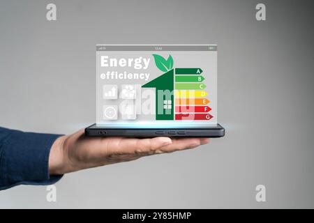 Concetto di efficienza energetica. Persona che utilizza un tablet con l'icona di valutazione dell'efficienza energetica sullo schermo virtuale per l'etichetta aud relativa alla tariffa di costruzione di edifici a risparmio energetico Foto Stock