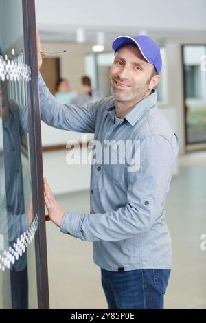 un lavoratore professionale felice ripara finestre metalliche in plastica Foto Stock