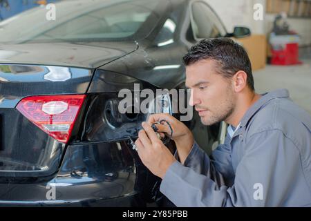 l'uomo sta riparando la luce posteriore Foto Stock