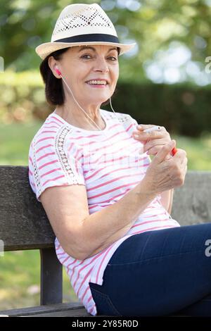 donna matura sorridente che ascolta musica all'aperto Foto Stock