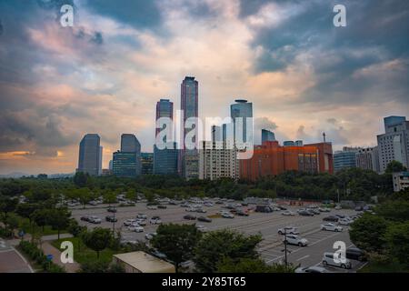 Skyline serale di Yeouido, Seoul, con alti grattacieli contro le nuvole spettacolari e un tranquillo parcheggio sottostante. Foto Stock