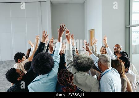 Un gruppo multietnico di colleghi che alzano le mani in un gruppo di cinque persone, celebrando il lavoro di squadra, il successo e la collaborazione in un ufficio moderno Foto Stock