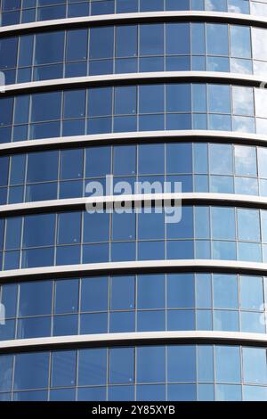 Un edificio moderno che mostra un cielo blu vibrante che si riflette splendidamente nelle sue grandi finestre, creando un incredibile effetto visivo Foto Stock