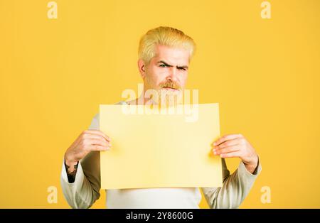 Il giovane mostra un foglio di carta nella fotocamera su uno sfondo a colori. Copia spazio. Foto Stock