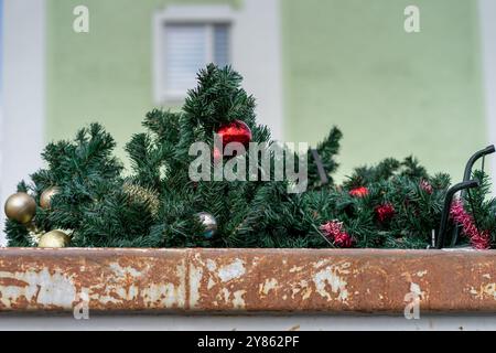 Abeti di plastica smaltiti decorati con palle di Natale rosse in un contenitore della spazzatura. Foto Stock