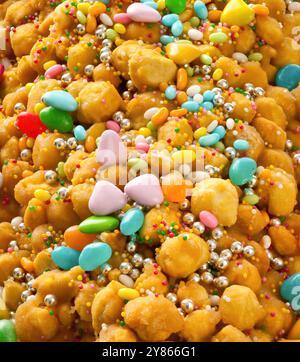 Strufoli, tipiche palle dolci italiane cosparse di zucchero colorato, miele e dragees d'argento, sparate dall'alto Foto Stock