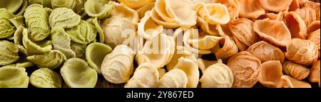 Colorate orecchiette crude in verde, bianco e arancione. Perfetto per gli amanti della cucina mediterranea. Un tocco di sapore per qualsiasi dieta Foto Stock