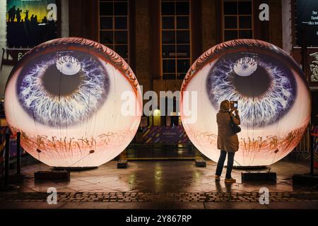 Essen, NRW, Germania. 2 ottobre 2024. I visitatori interagiscono con l'installazione "Oculus" degli artisti H:e:M (Italia) fuori dal Teatro Grillo. Due sfere giganti brillano a forma di due occhi che guardano verso il cielo. Serata di apertura dell'annuale Essen Light Festival con 16 installazioni di luci su larga scala in tutta la città. Il festival è gratuito e si svolge ogni sera dal tramonto alle 23:00, dal 2 al 13 ottobre 2024. Crediti: Imageplotter/Alamy Live News Foto Stock