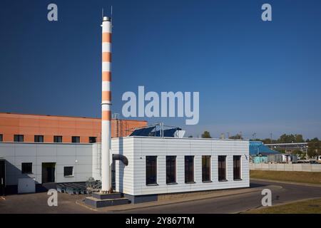 Moderno edificio caldaie con tubi di vapore per fornire riscaldamento e acqua calda a grandi edifici industriali con sistema di riscaldamento ad acqua solare sul tetto Foto Stock