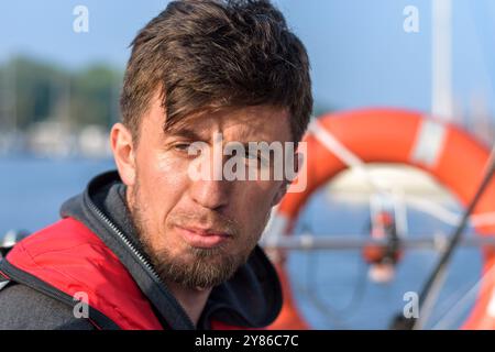 Un giovane brunetta premuroso e bello davanti a un salvagente su uno yacht. Bassa profondità di campo. Primavera-estate, giorno Foto Stock