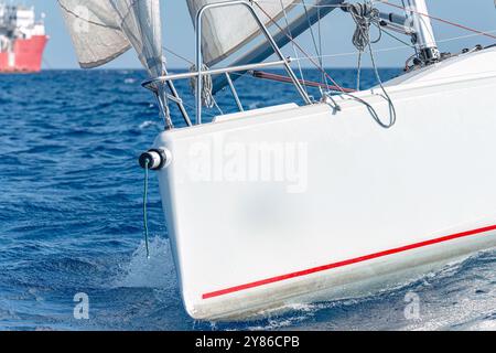 Barca a vela bianca che taglia le acque blu dell'oceano in una giornata di sole Foto Stock