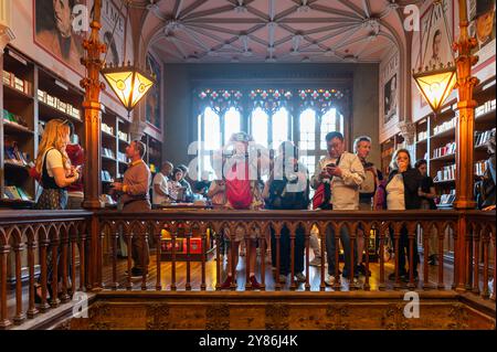 Porto, Portogallo - 12 settembre 2024: Un gruppo di persone ammira il design intricato e i libri in una storica libreria. Foto Stock