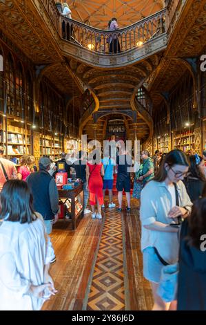 Porto, Portogallo - 12 settembre 2024 : i visitatori esplorano una vivace libreria piena di libri diversi in un'atmosfera accogliente Foto Stock