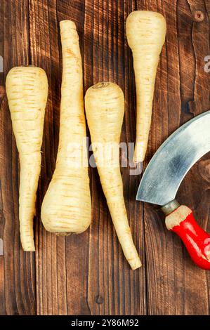 Il pastinaca cruda e cruda affonda le radici su un vecchio tavolo rustico in legno. Verdure fresche. Foto Stock