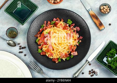 Pasta con pancetta arrosto servita su un piatto nero, pasta alla carbonara. Piatto di pasta italiana. Vista dall'alto. Foto Stock