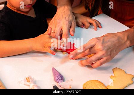 Un bambino sta preparando biscotti con un adulto. L'adulto sta aiutando il bambino a preparare un biscotto a forma di zucca Foto Stock