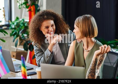 Due colleghi si godono un momento di luce, abbracciando la propria identità in un'area di lavoro accogliente. Foto Stock